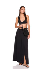 Woman wearing a black outfit with a belt and mini neoprene cross body bag bag on a white background