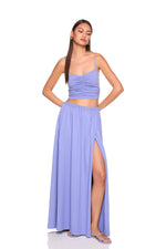 Woman wearing a purple two-piece outfit with a top and long skirt on a white background