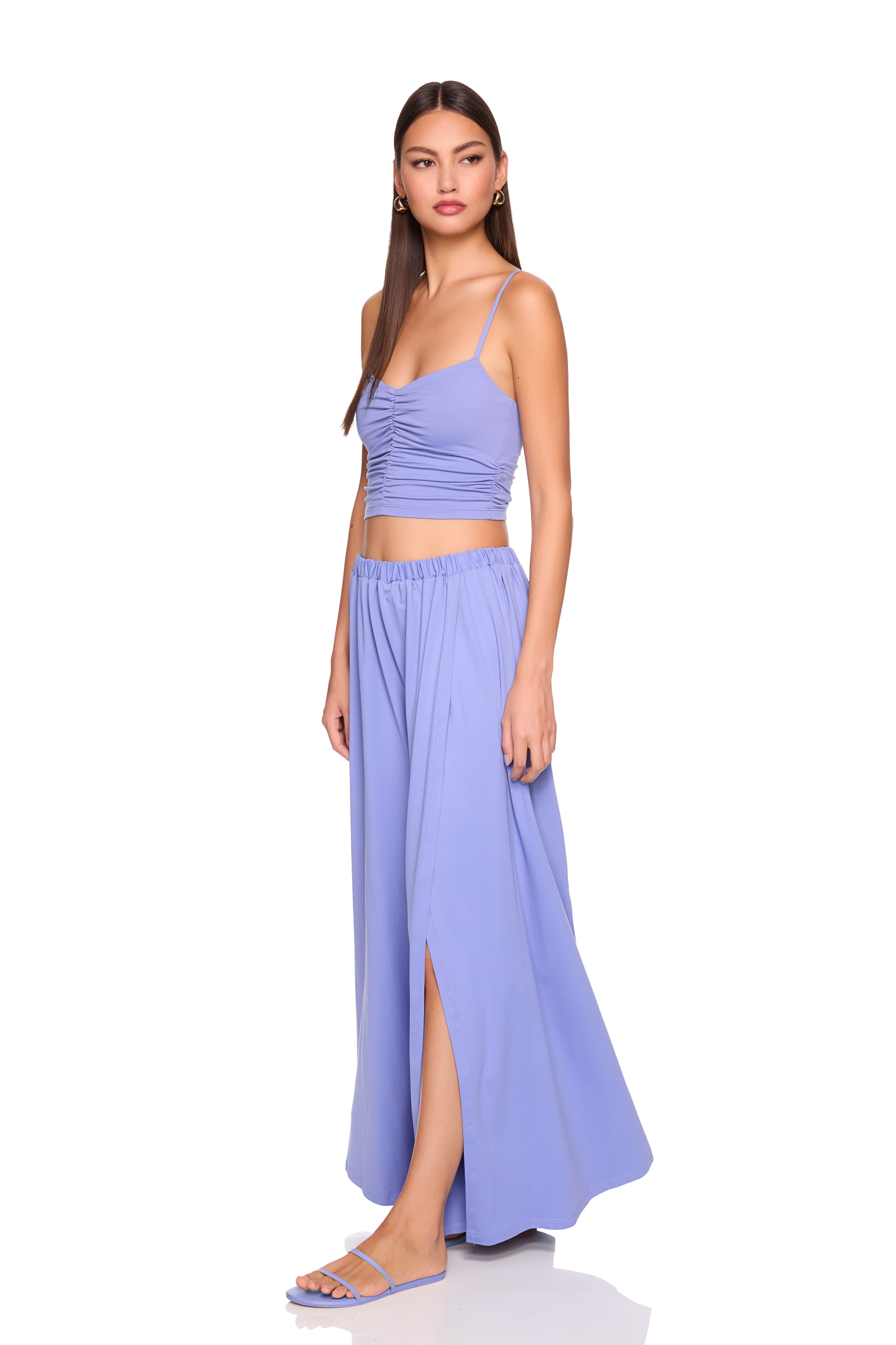 Woman wearing a lavender top and long skirt on a white background