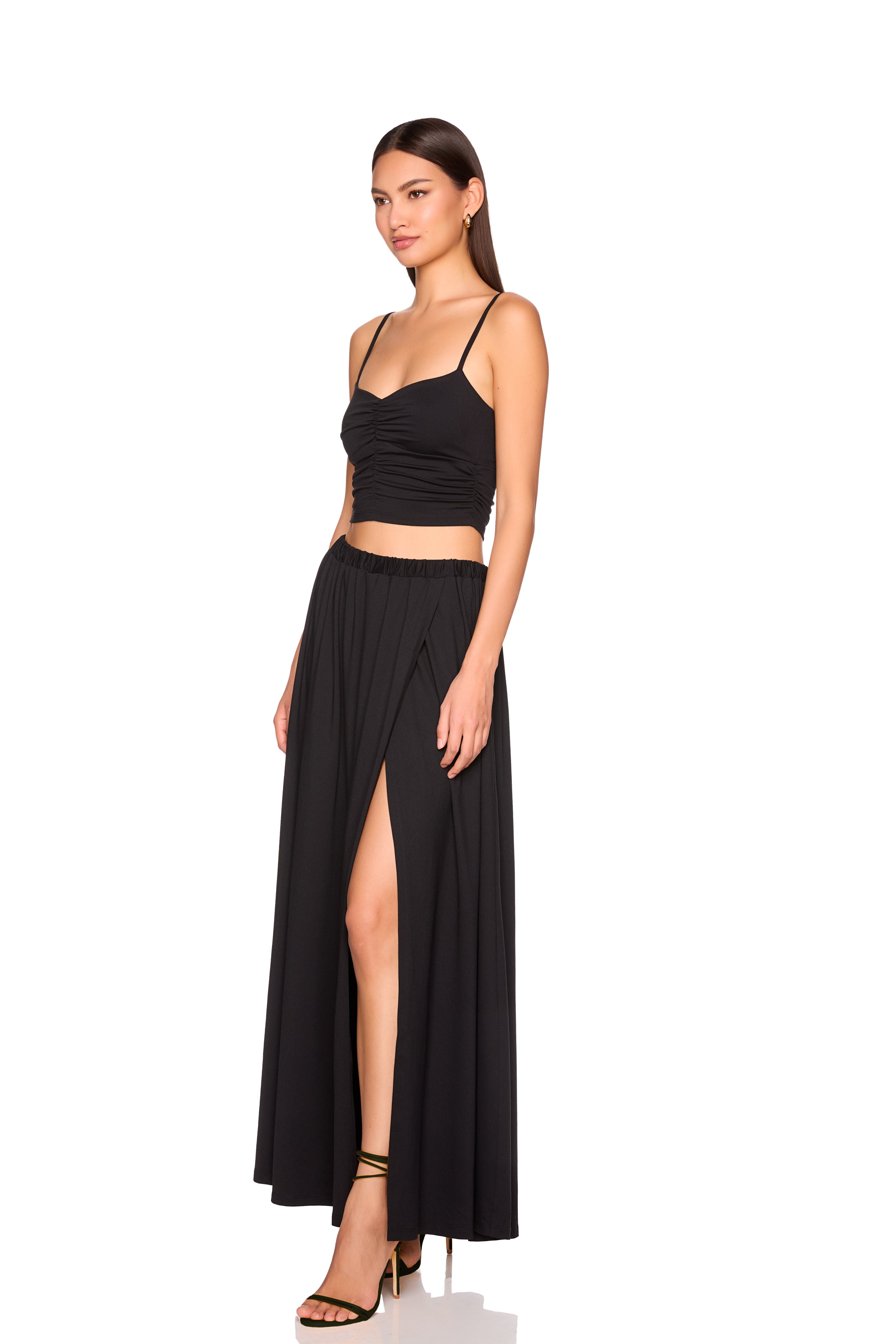 Woman wearing a black outfit with a crop top and long skirt on a white background