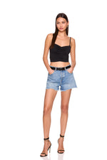Woman wearing a black crop top and denim shorts on a white background