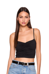 Woman wearing a black ruched top and blue jeans on a white background