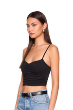 Woman wearing a black tank top and blue jeans on a white background