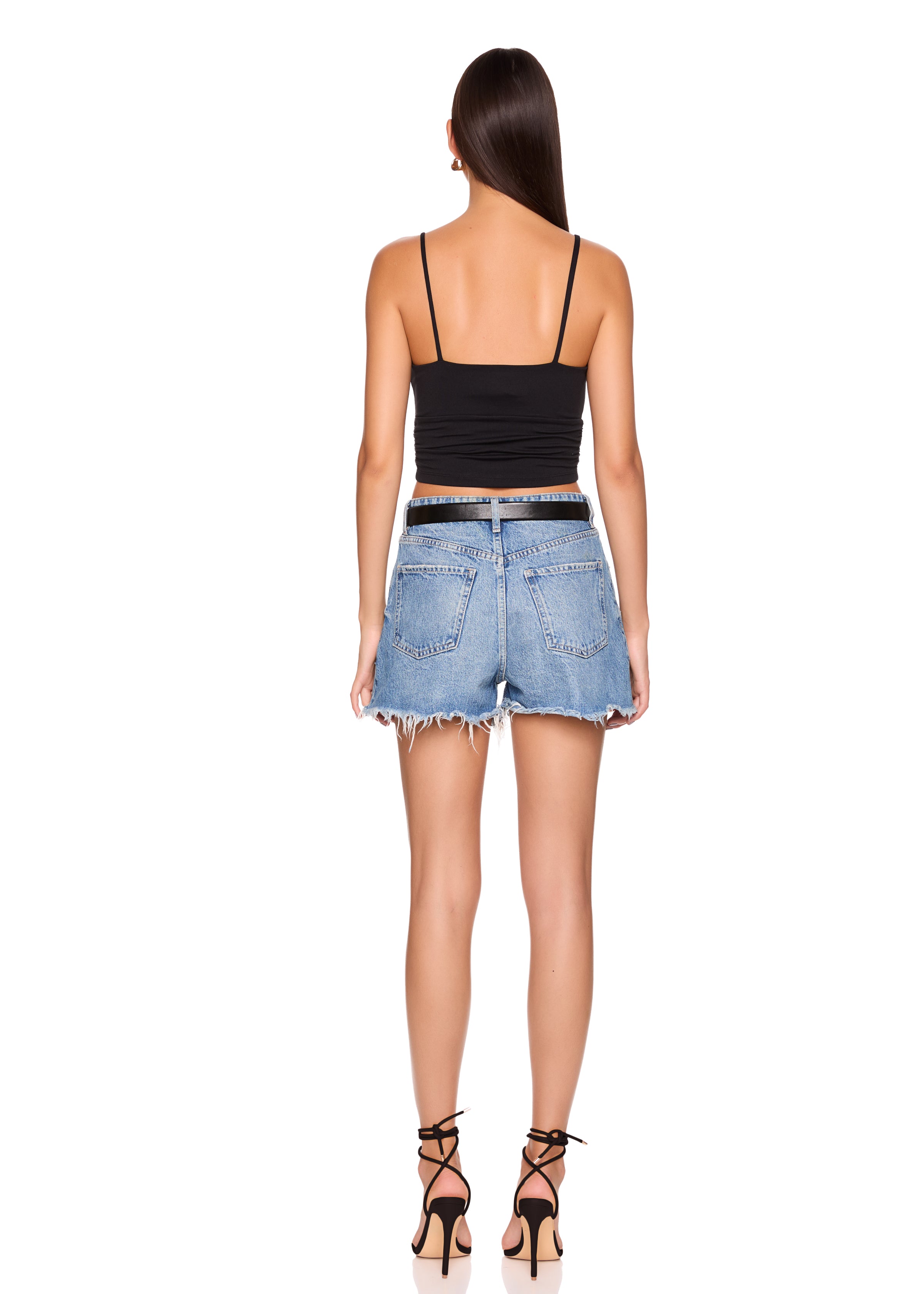Woman wearing a black top and denim shorts on a white background
