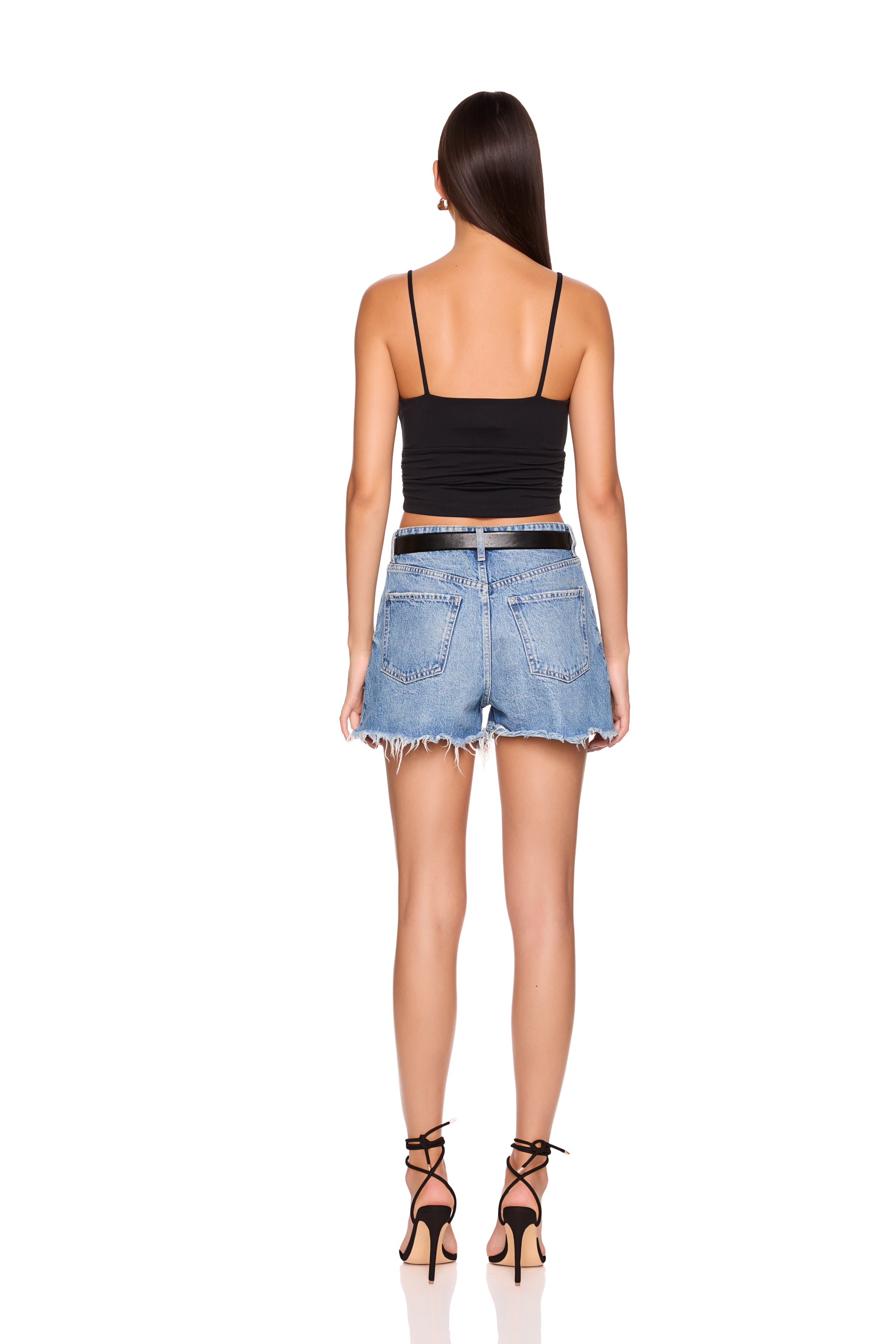 Woman wearing a black top and denim shorts on a white background