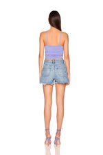 Woman wearing a purple tank top and denim shorts on a white background