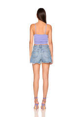 Woman wearing a purple tank top and denim shorts on a white background