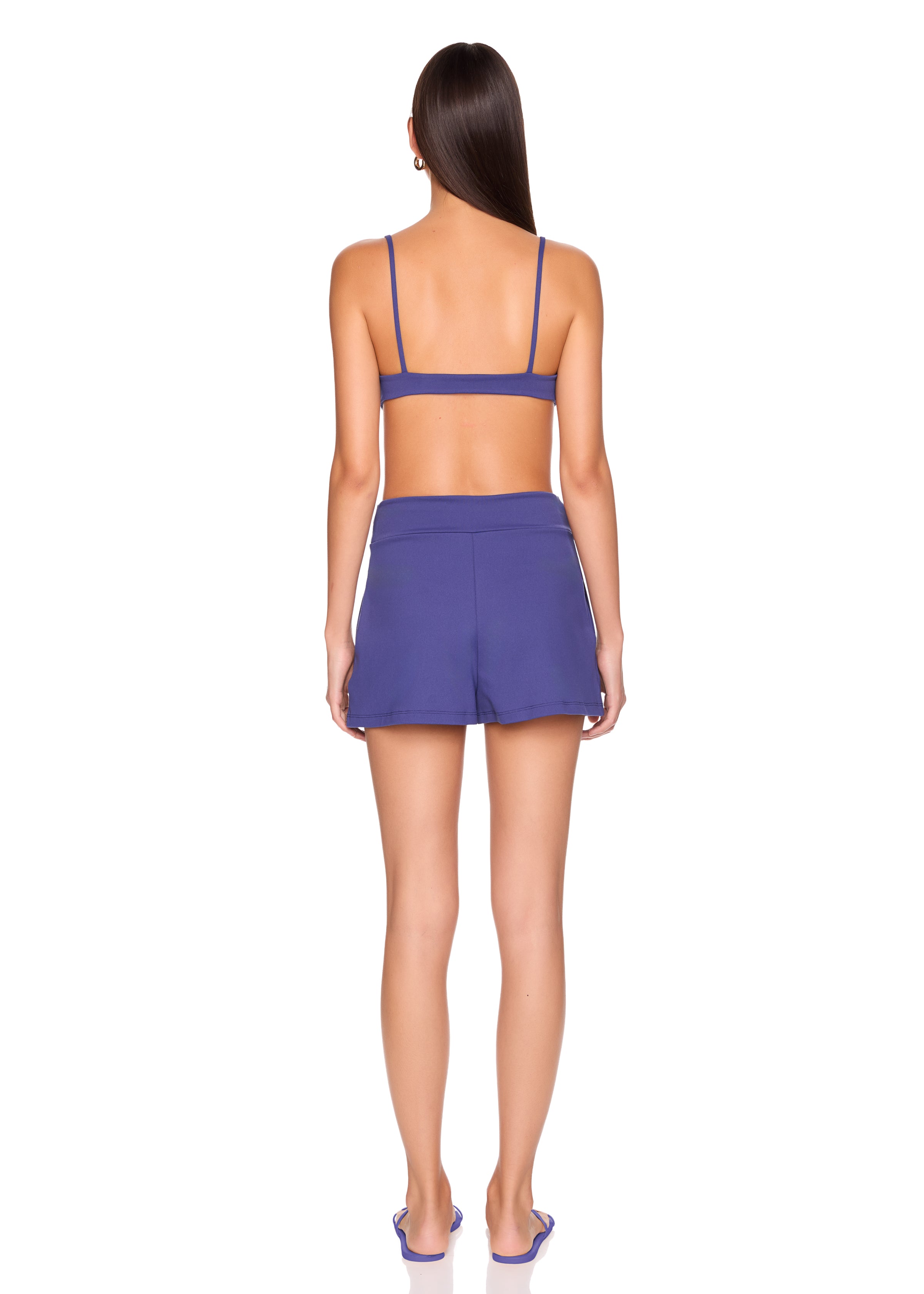 Person wearing a purple sports bra and shorts set on a white background