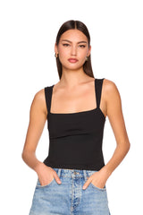 Woman wearing a black tank top and blue jeans on a white background