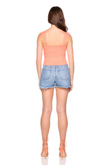 Woman wearing a peach strapless top and denim shorts on a white background