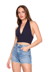 Woman wearing a navy halter top and denim shorts on a white background