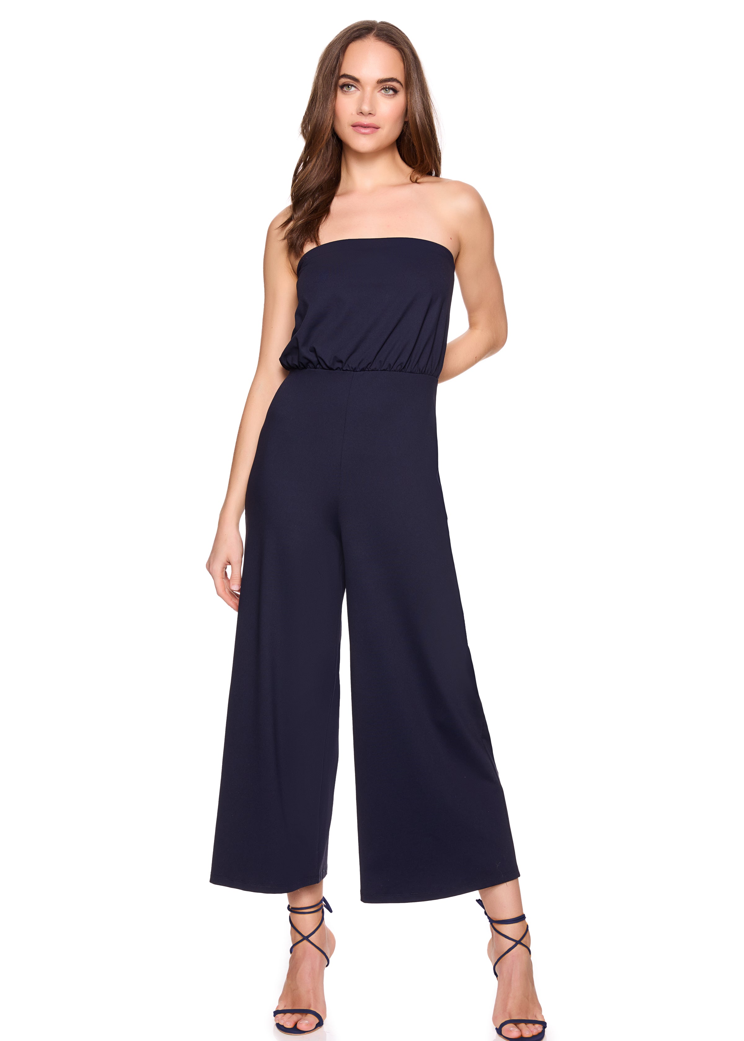 Woman wearing a strapless navy jumpsuit on a white background
